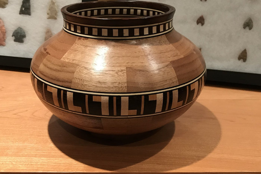 Segmented bowl with a feature ring spelling the letter L, photographed on a maple table