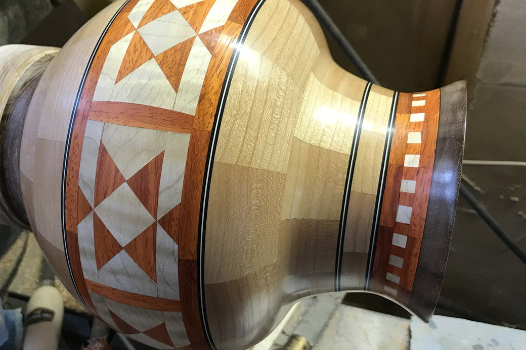 A patterned segmented vessel still mounted on the lathe, being turned